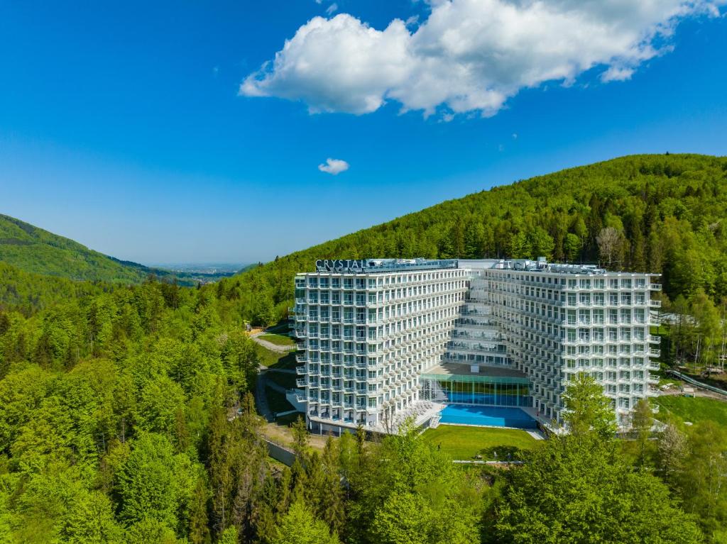 a large white building in the middle of a forest at Crystal Mountain Hotel Wisła in Wisła