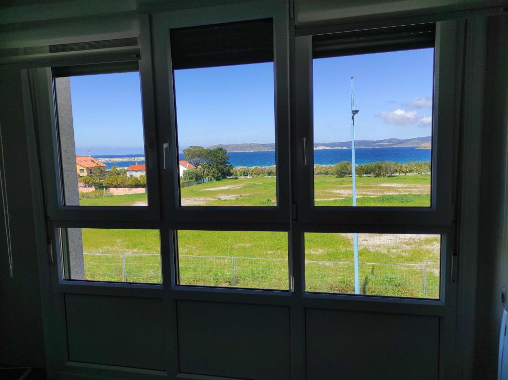 een kamer met een raam met uitzicht op het water bij Piso en primera linea de Playa en Laxe in Laxe