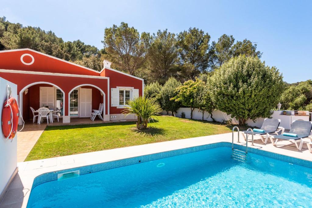 a villa with a swimming pool and a house at Villas Galdana Palms in Cala Galdana