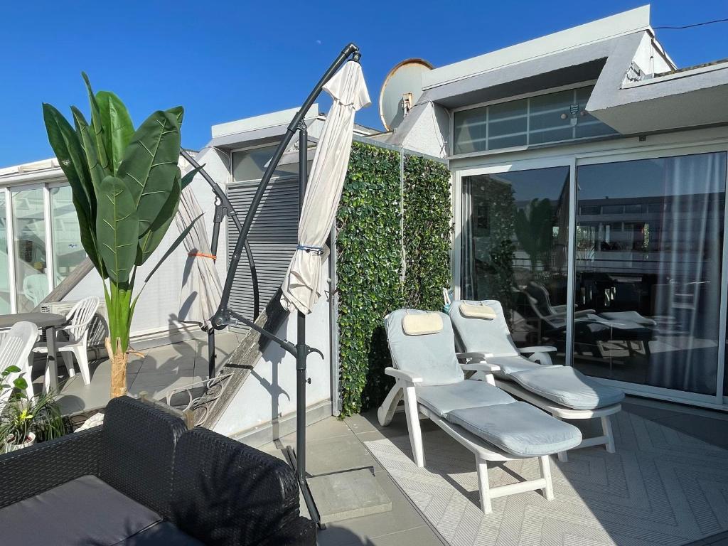 une terrasse avec des chaises et un parasol dans une maison dans l'établissement Naturist Port Ambonne Melrose View, au Cap d'Agde