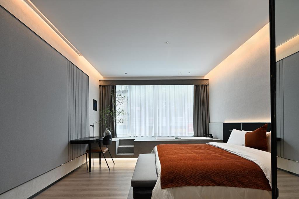 1 dormitorio con cama, escritorio y ventana en LIA Hotel Shenzhen Qianhai Baoan Center Turnaround Metro Station, en Bao'an