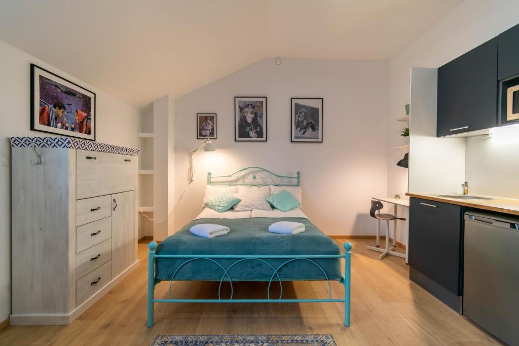 een kleine slaapkamer met een blauw bed en een keuken bij Apartments24 Spordi in Rakvere
