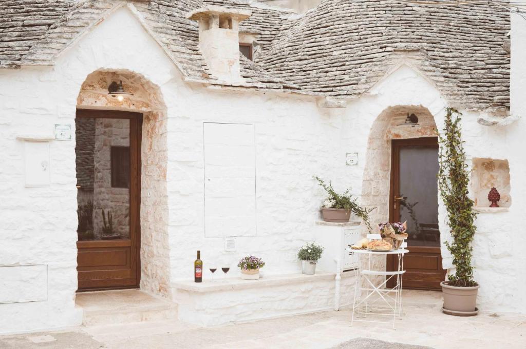 Biały dom z brązowymi drzwiami i roślinami w obiekcie I trulli di Dioniso - Incipit w Alberobello