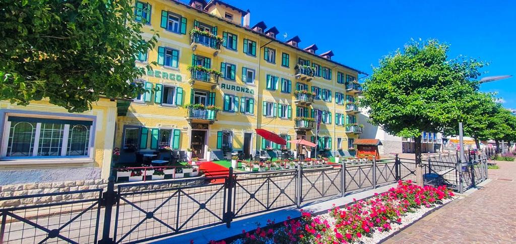 a yellow building with flowers in front of it at Hotel Auronzo in Auronzo di Cadore