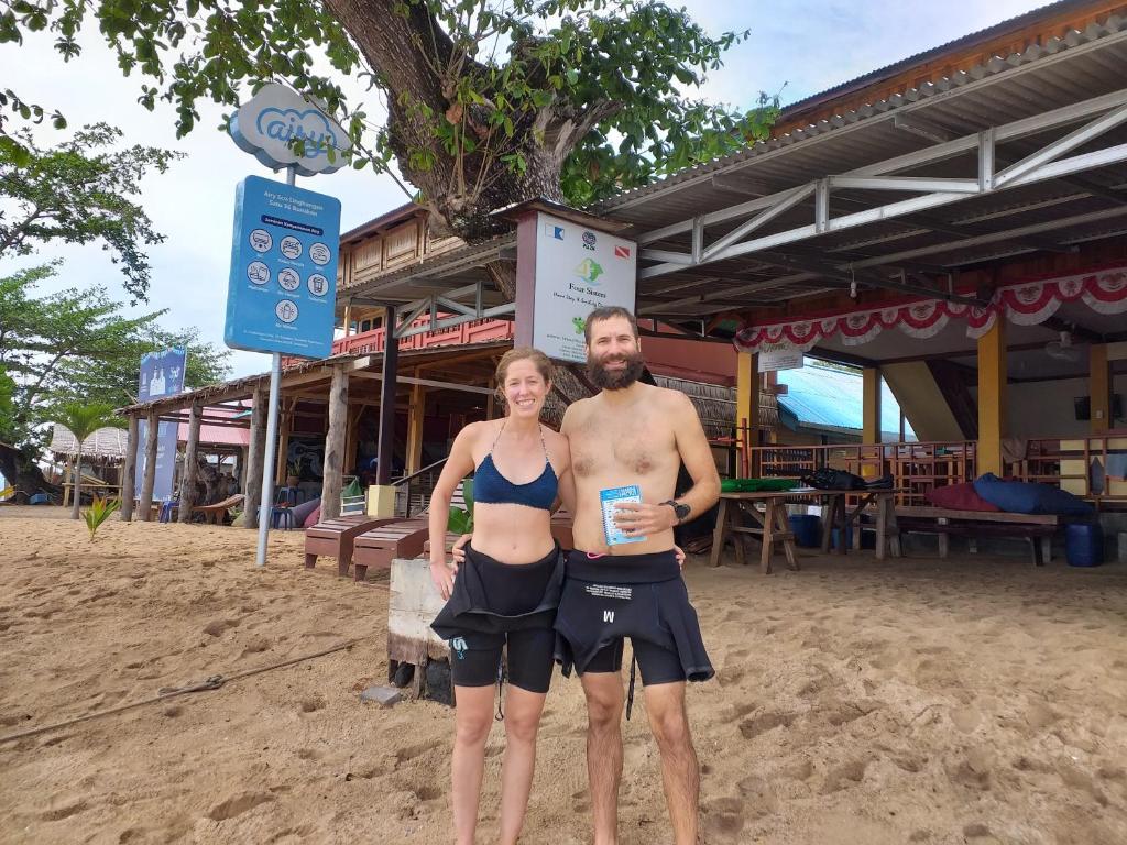 a man and a woman standing on the beach at 4 Sisters Divers in Bunaken