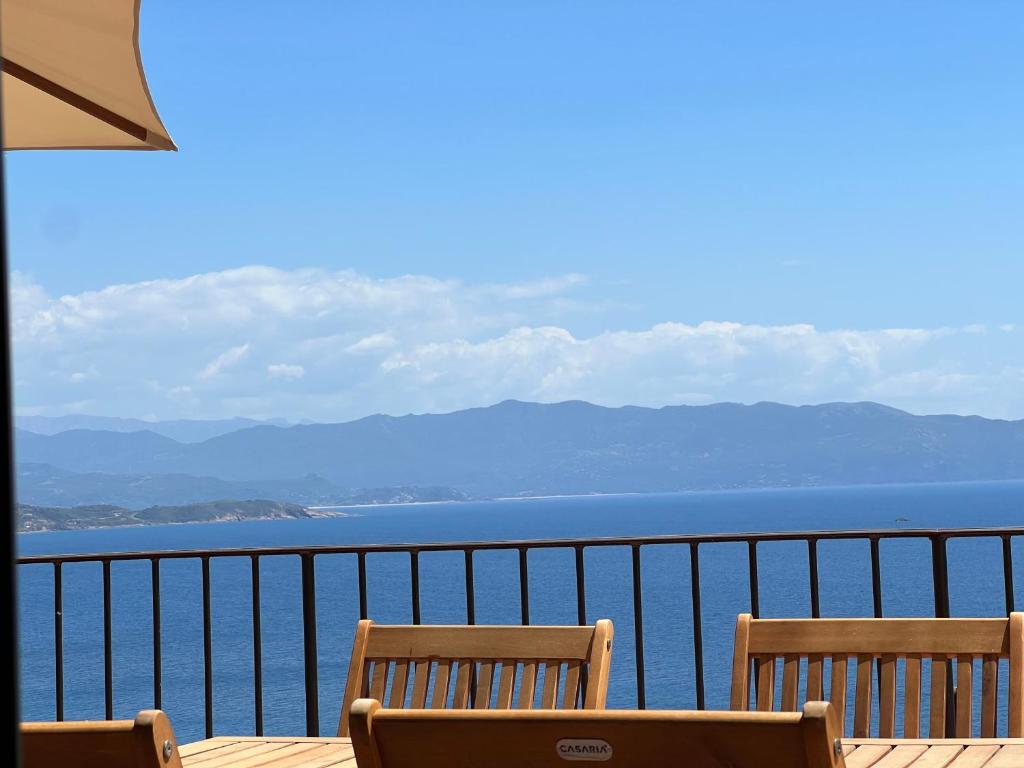 Duas cadeiras sentadas numa varanda com vista para a água em Résidence Eole em Cargèse