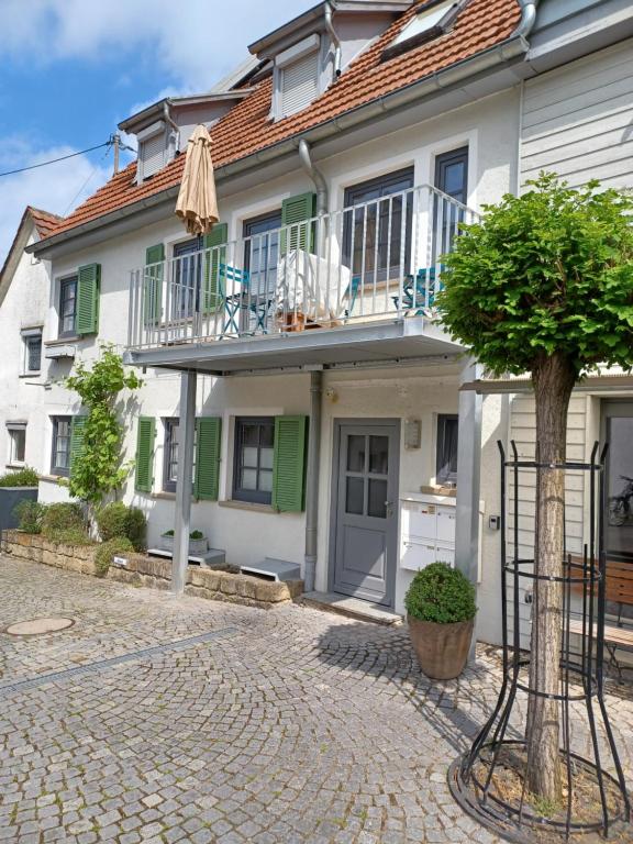 a house with a balcony and a tree in front of it at Gemütlichkeit über der Weinrebe- 3Zi. Zi. Fewo. in Stetten