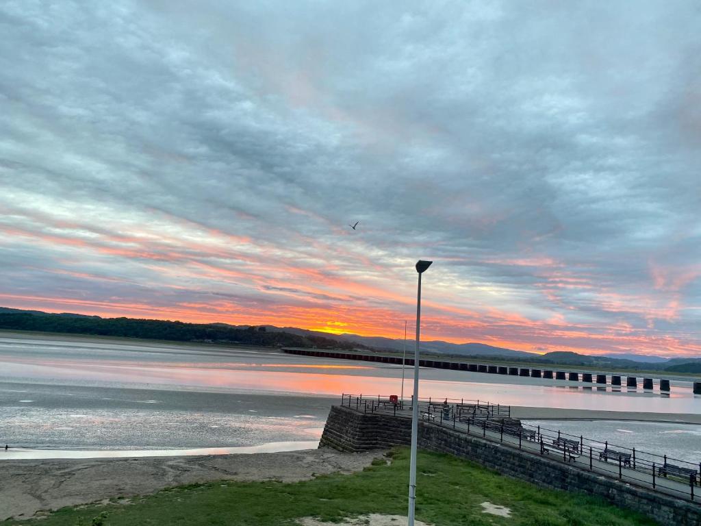 a sunset over the water with a pier at Arnside sea view in Arnside