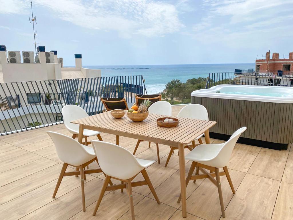 una mesa de madera y sillas en un balcón con vistas al océano en Luxury Penthouse Allonbay Village & SPA en Villajoyosa