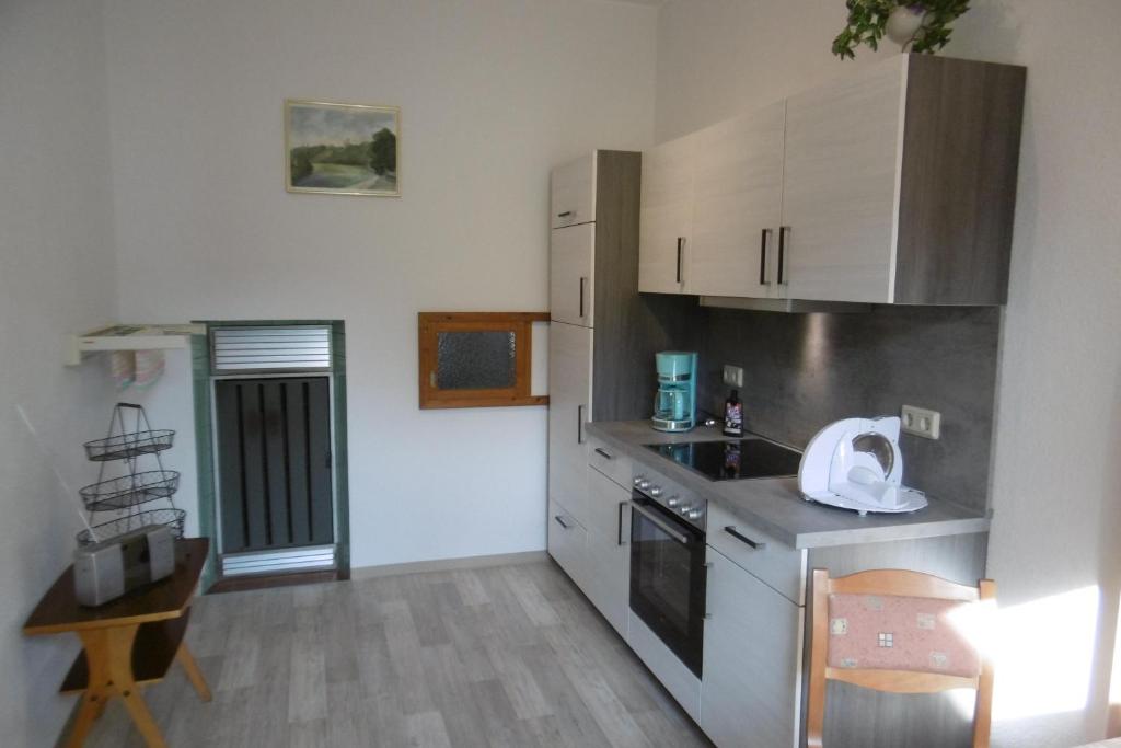 a kitchen with white cabinets and a table and a chair at Ferienwohnung Rauscher in Kurort Altenberg