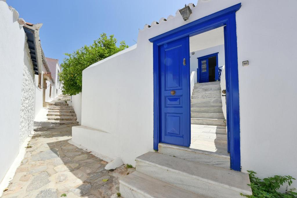 una porta blu su un edificio bianco con scale di Bexis Residences Hydra a Hydra