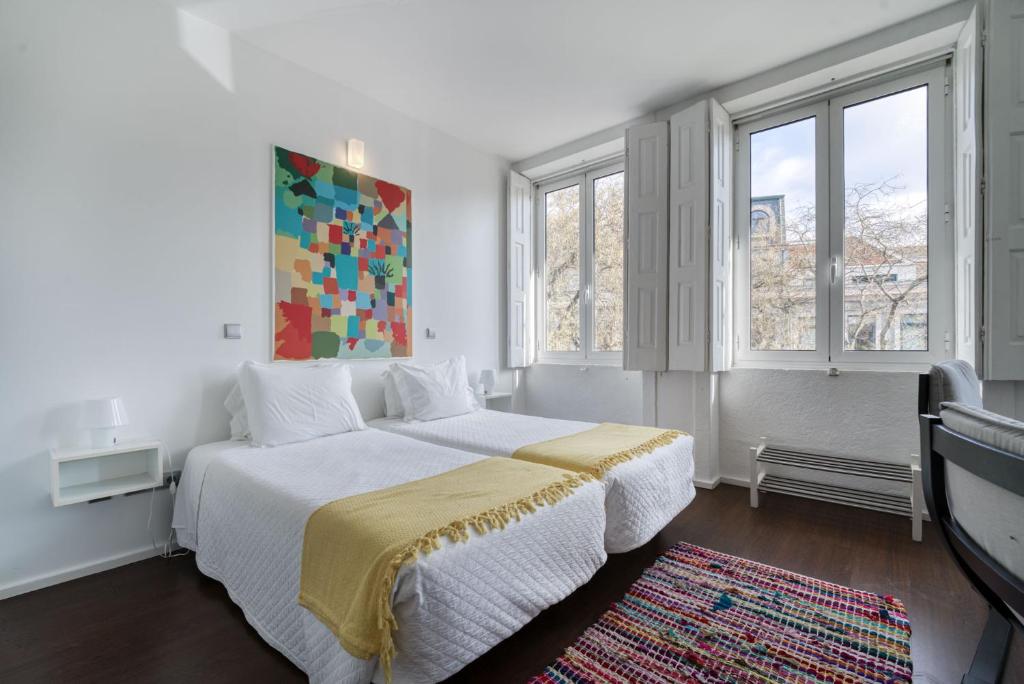 a bedroom with a large bed and two windows at Olala Fine Arts Studios in Porto