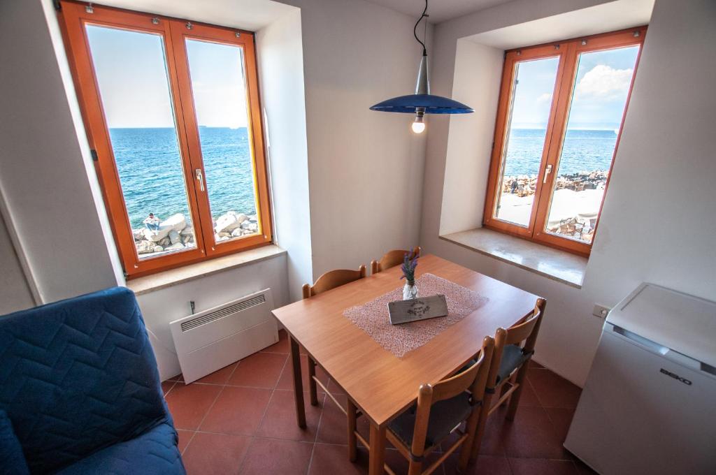 uma sala de jantar com uma mesa e duas janelas em Apartments Punta Piran em Piran