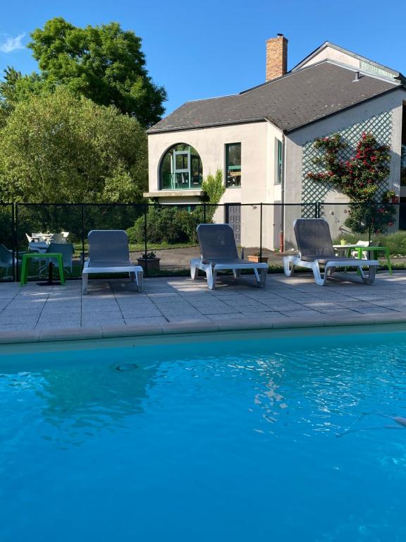 two lounge chairs sitting next to a swimming pool at Golf Hotel Colvert - Piscine extérieure et Room Service in Levernois