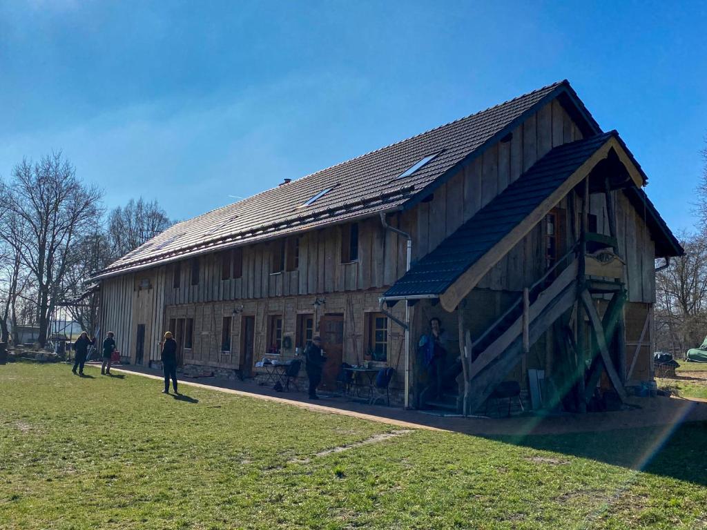 a large wooden barn with people standing outside of it at Scheunenherberge Schäfchenzählerei in Burg