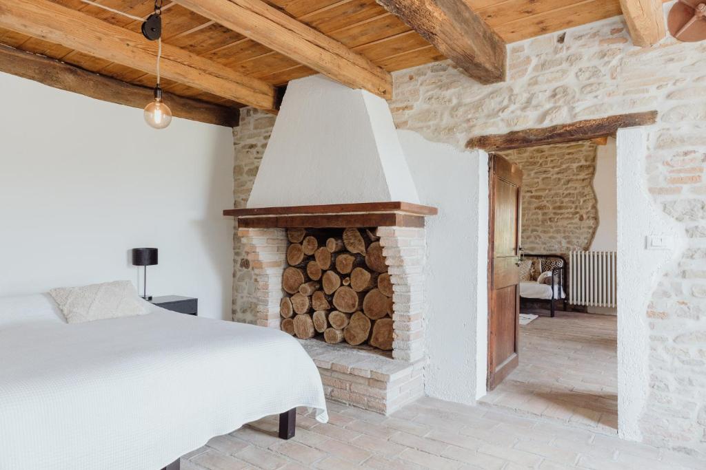 a bedroom with a bed and a fireplace with logs at Agriturismo Qui Voglio in Monte Roberto