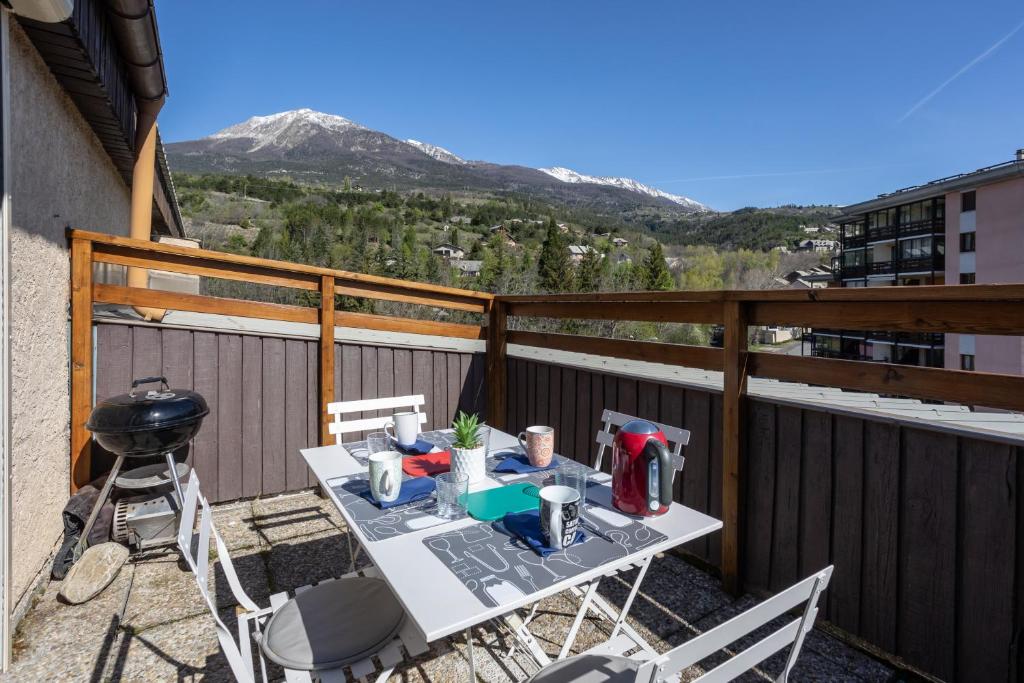 einen Tisch und Stühle auf einem Balkon mit Grill in der Unterkunft Terrasse des Lupins in Embrun