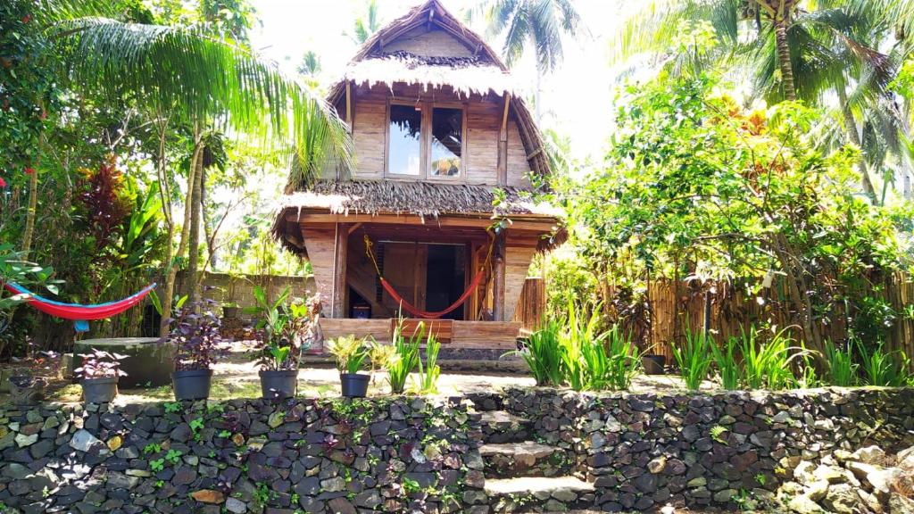 a wooden house with a fence and plants in front of it at Rumah Saung Batukaras in Batukaras