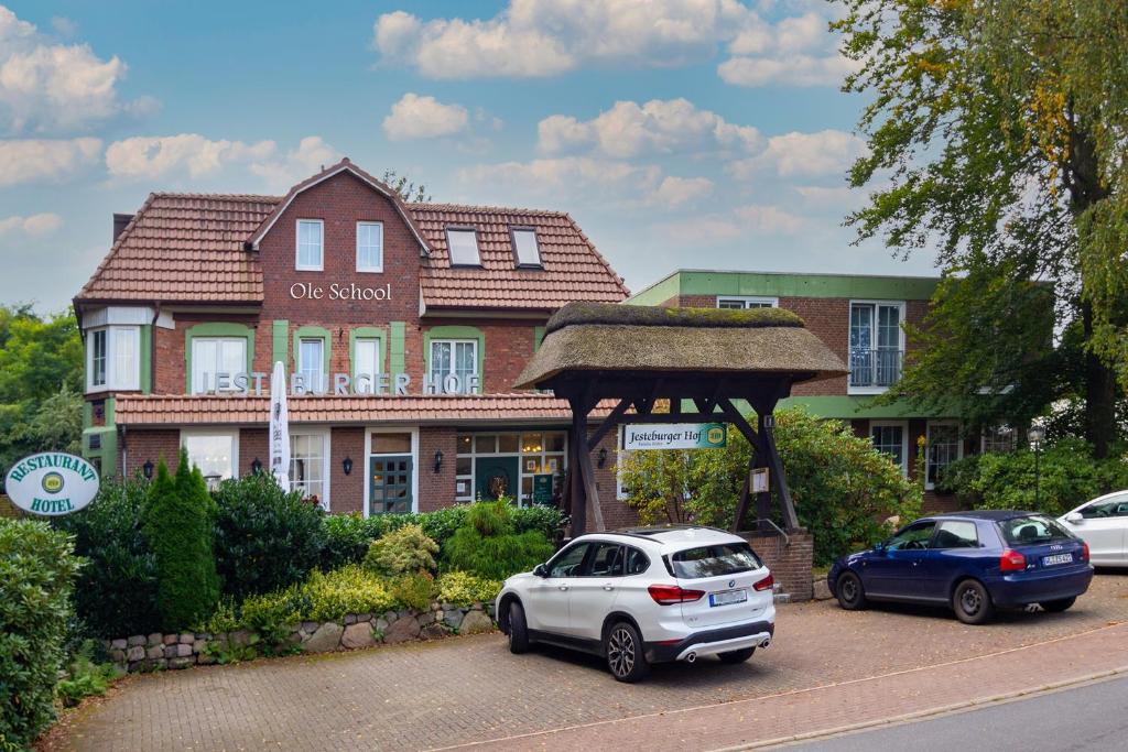 dos autos estacionados en un estacionamiento frente a una casa en Hotel Jesteburger Hof en Jesteburg