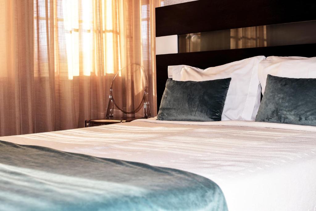um quarto com uma cama grande com lençóis brancos e almofadas em Residencial Portas do Sol em Valença