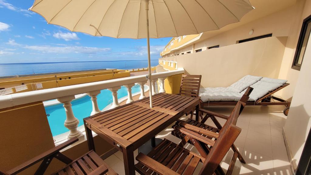 a balcony with a table and chairs and an umbrella at Apt con piscina La Laja, La Restinga (El Hierro) in La Restinga