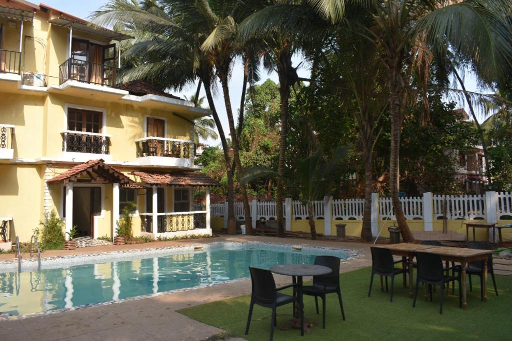 a pool with tables and chairs next to a building at Villa Fatima Comfort in Calangute