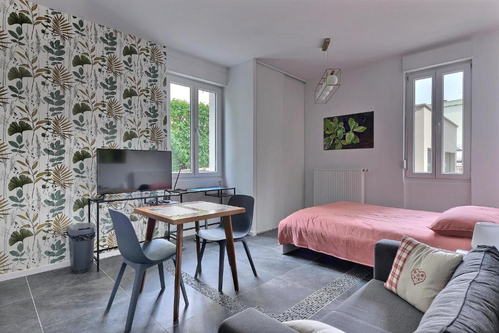 - une chambre avec un lit, une table et une télévision dans l'établissement "Urbaine Jardin" Charmant studio idéalement situé "Les Péri-Urbaines", à Riedisheim