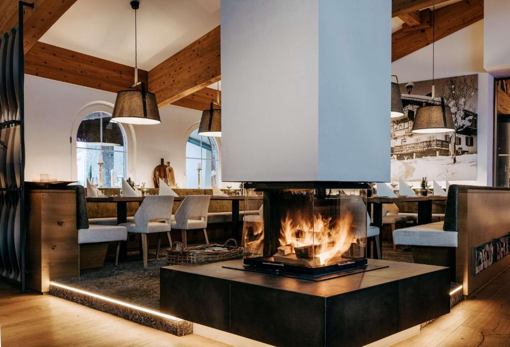 a fireplace in the middle of a room with a restaurant at Grand Tirolia Kitzbühel - Member of Hommage Luxury Hotels Collection in Kitzbühel