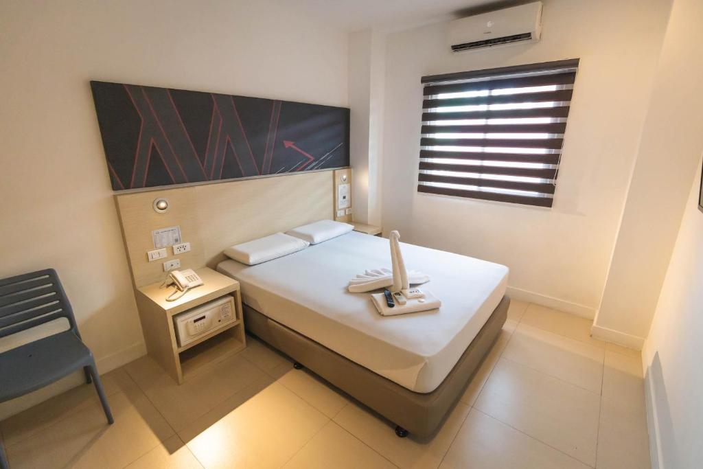 Un pequeño dormitorio con una cama blanca y una ventana en Wow Budget Hotel Cubao en Manila