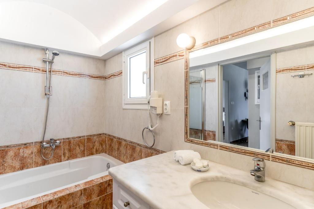 a bathroom with a tub and a sink and a mirror at Amarie House with Sea View & Sunset View in Oia