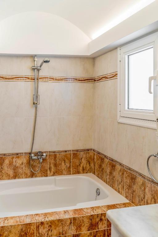 a bathroom with a tub and a window at Amarie House with Sea View & Sunset View in Oia