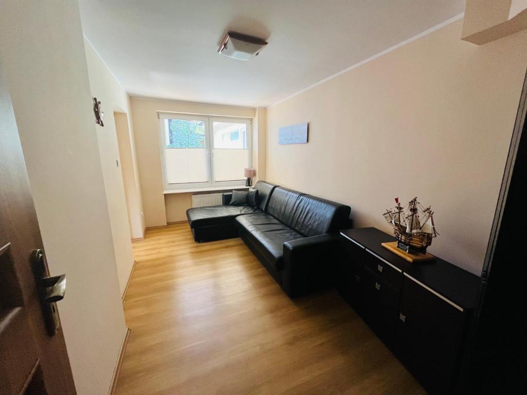 a living room with a black leather couch and a window at Apartament Bryza, Willa Perla 100m od morza in Gdańsk