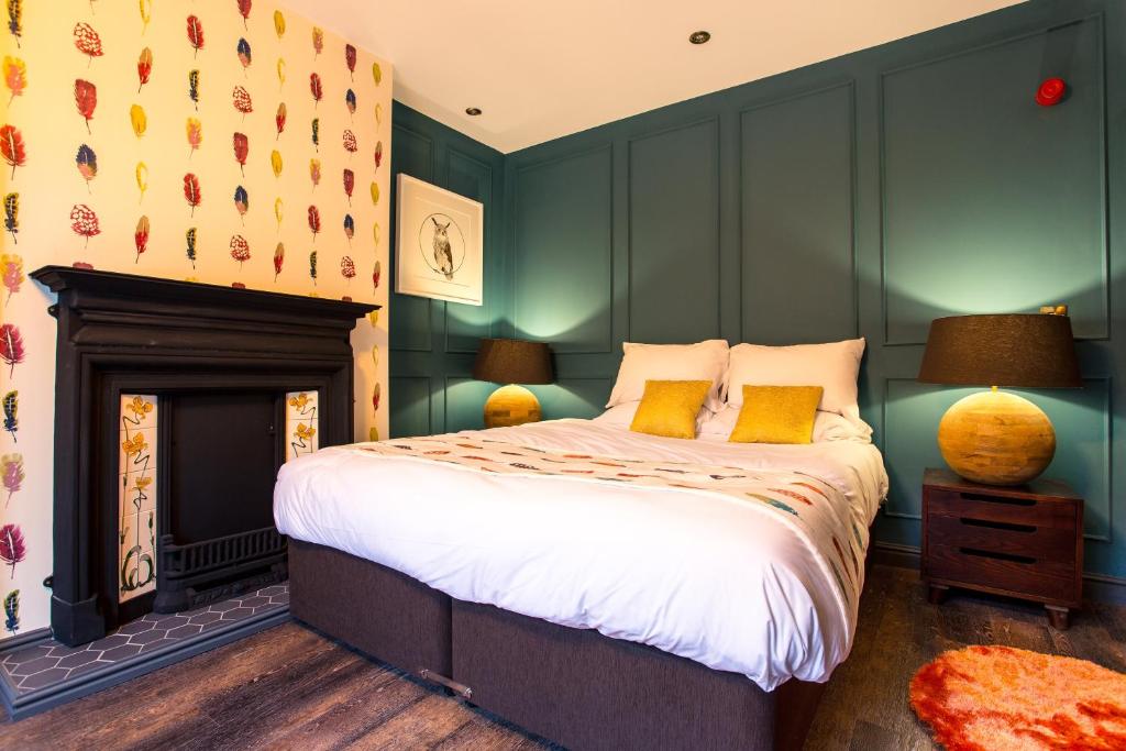 1 dormitorio con 1 cama con paredes verdes y chimenea en Eagle and Child, Ramsbottom en Bury