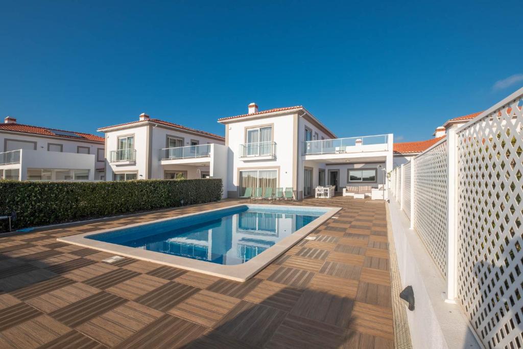 a villa with a swimming pool in front of a house at Vila do Golfe Villa in Casal da Lagoa Seca