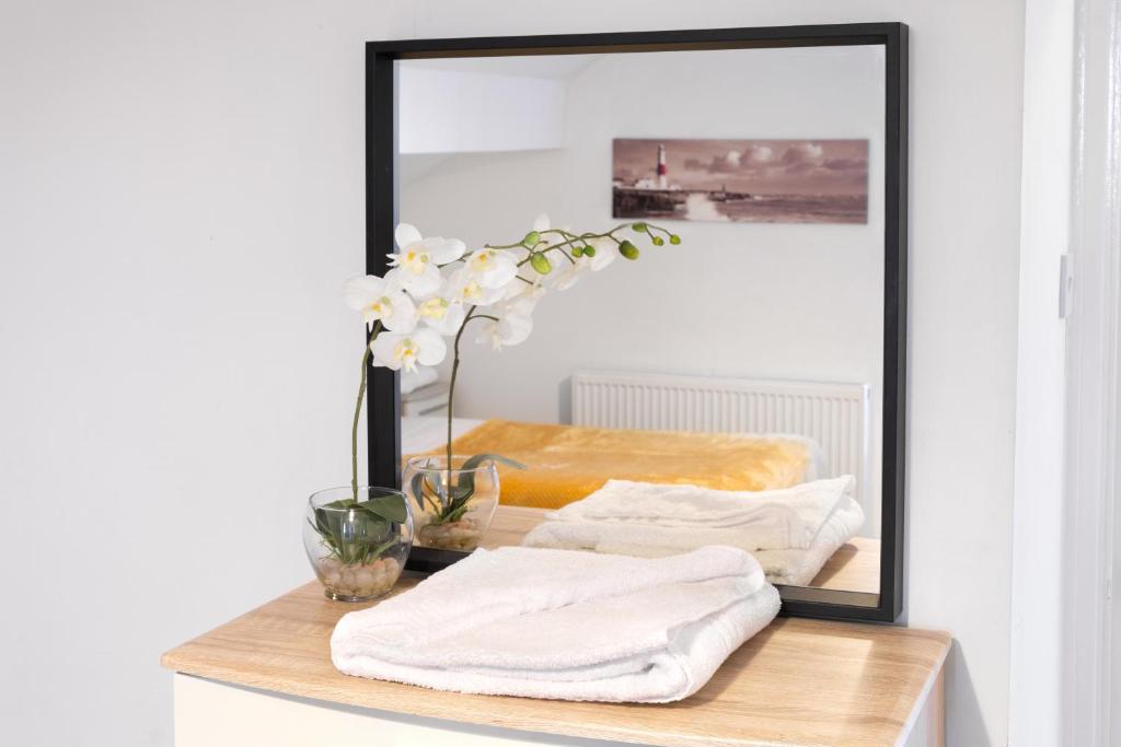 un espejo sentado sobre una mesa con toallas en Spacious Apartment Close To City Centre, en Leeds