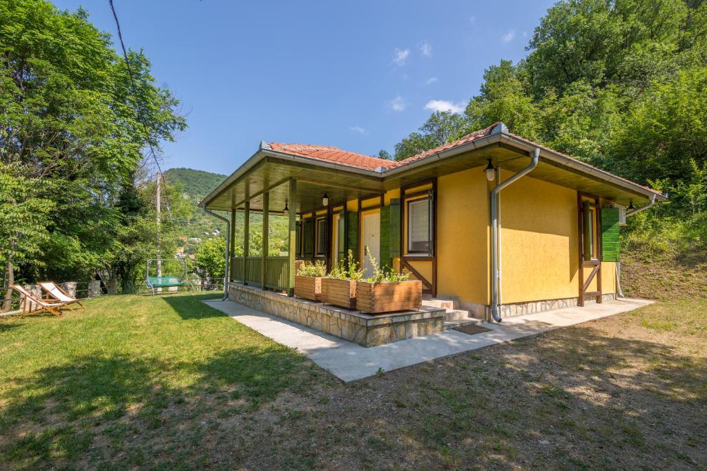 una pequeña casa amarilla en medio de un patio en Vila Camelia en Golubac