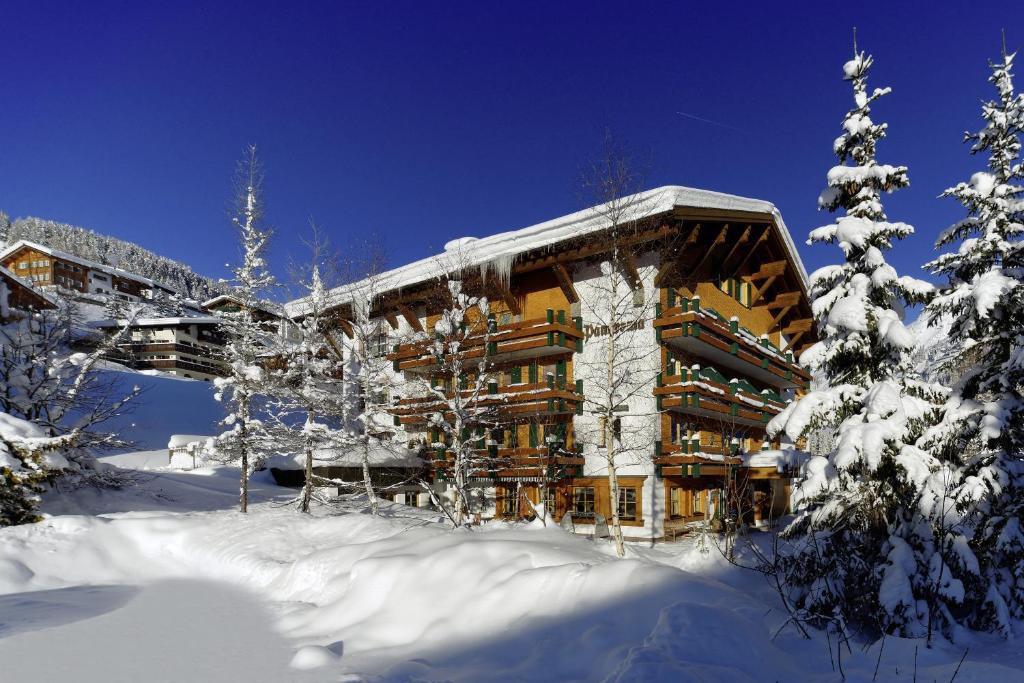 a large building in the snow with snow covered trees at Hotel Garni Panorama in Lech am Arlberg