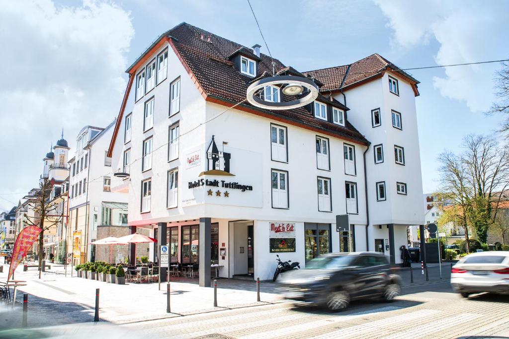 a car driving past a white building on a street at Hotel Stadt Tuttlingen in Tuttlingen
