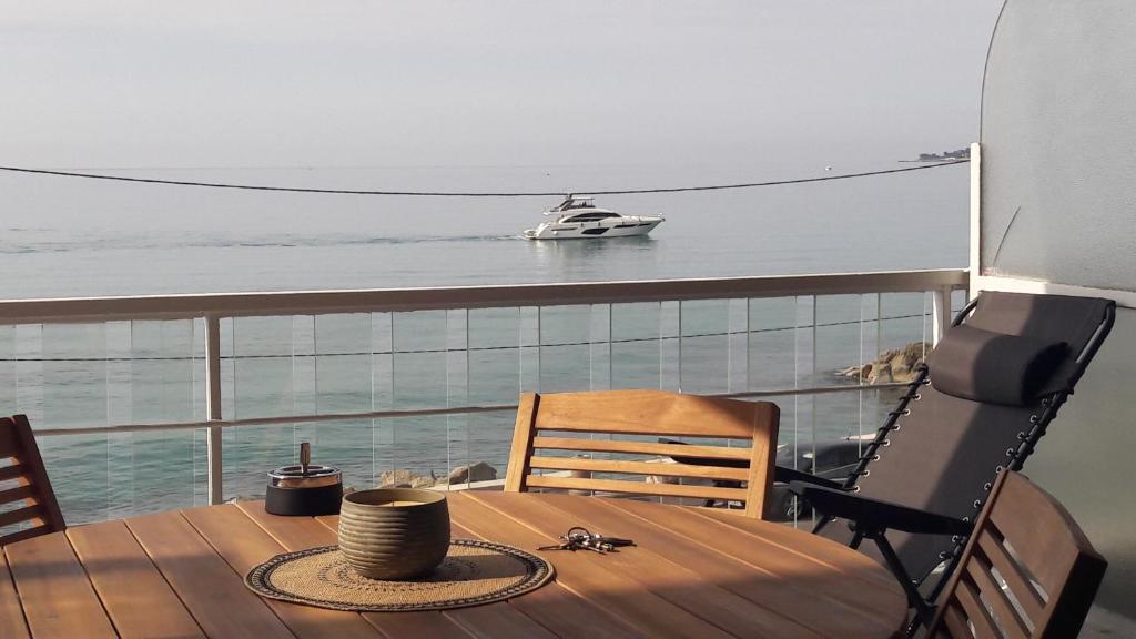 a table and chair on a balcony with a boat in the water at Splendide studio front de mer in Menton