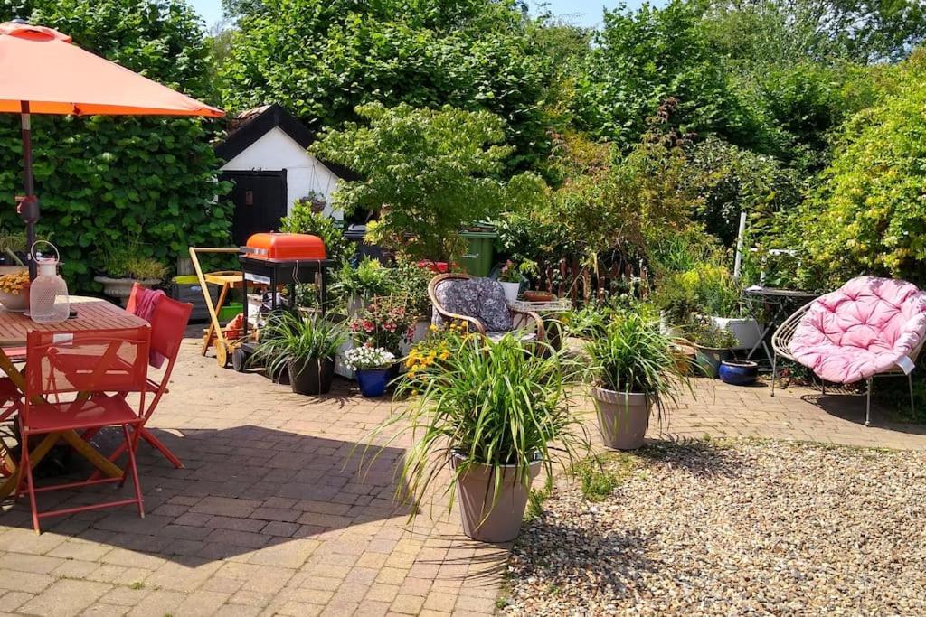 a patio with potted plants and a table and chairs at Cobweb Cottage in Spooner Row