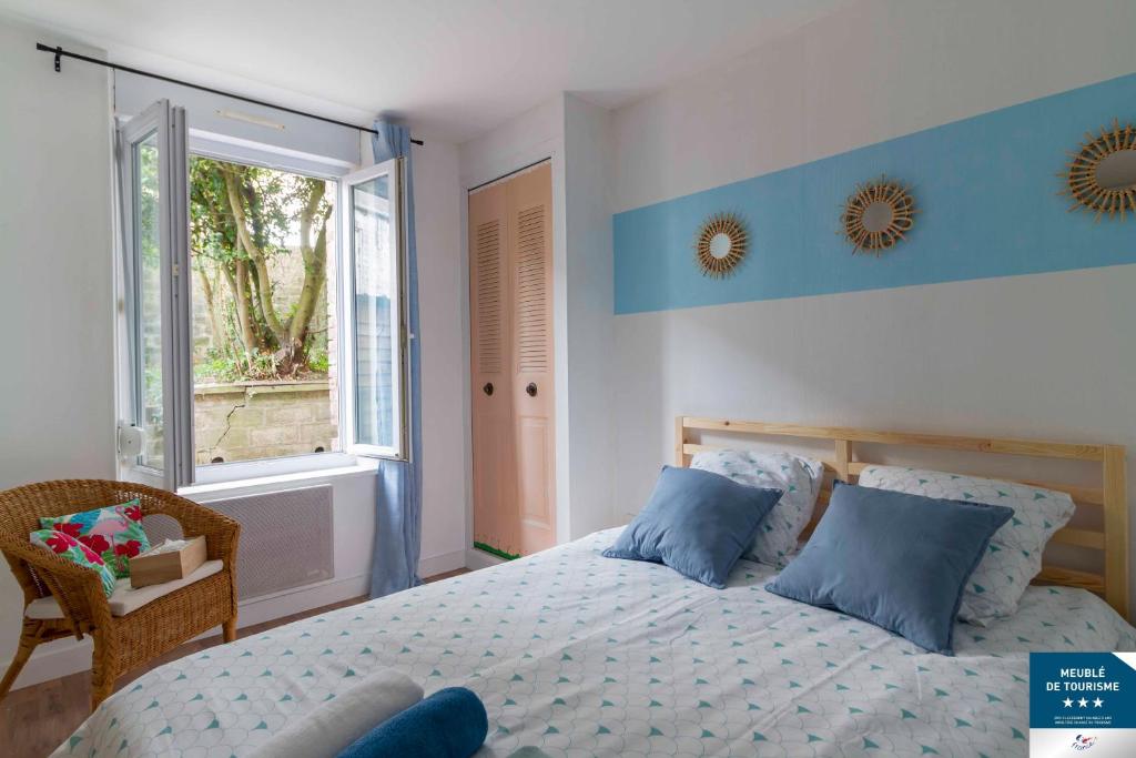 Un dormitorio con una cama con almohadas azules y una ventana en Le Grand Appart&#39; proche commerces, en Flers