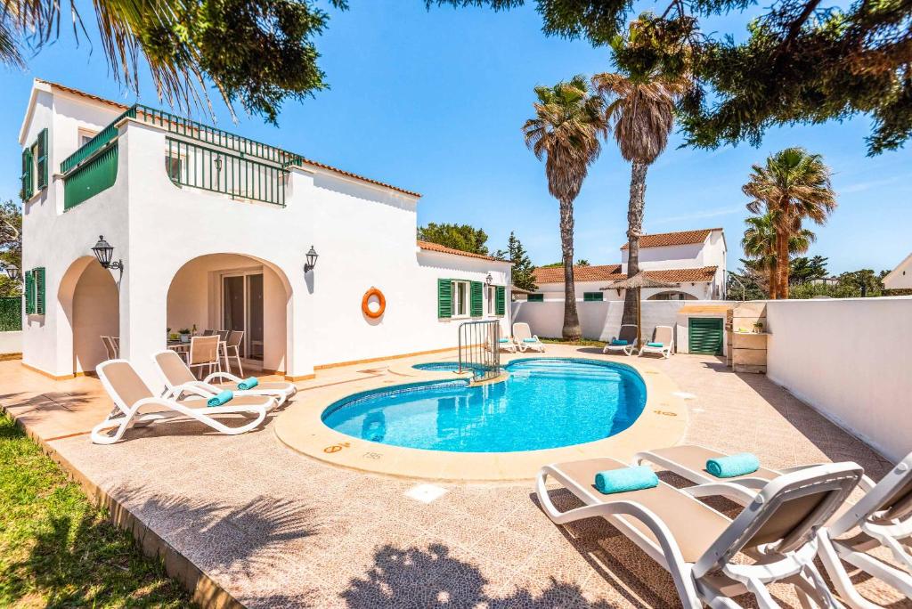 a villa with a swimming pool and lounge chairs at Villa Ingrid in Cala en Forcat