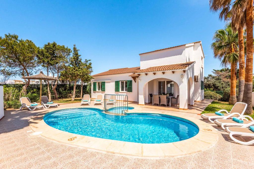a villa with a swimming pool in front of a house at Villa Raquel Blanes in Cala en Forcat
