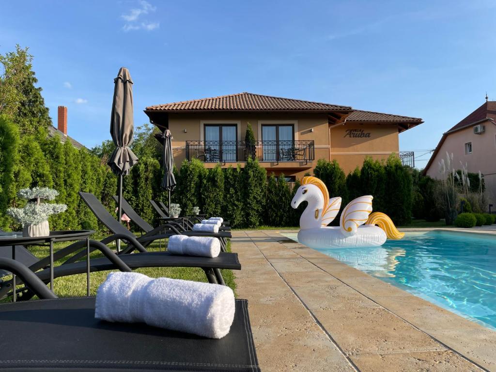 a backyard with a swimming pool with chairs and a house at Villa Aruba & Private SPA Suites in Keszthely