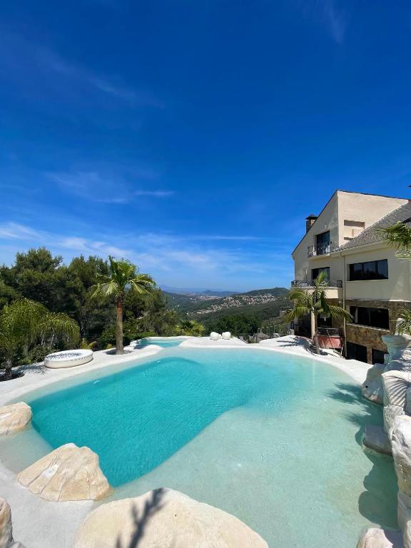 a large swimming pool with blue water in front of a building at Petit Mirador in Torrelles de Llobregat