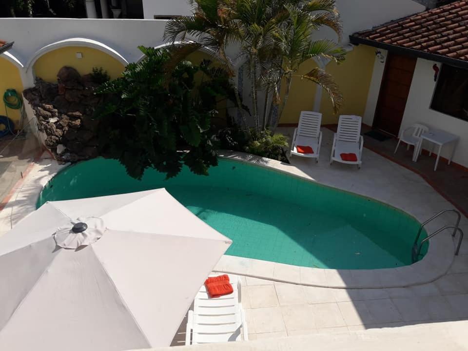 a swimming pool with a white umbrella and chairs at Hotel Casa Jardin in Asunción