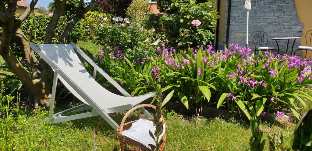 a white chair sitting in a garden with flowers at La Turr de Mezz- Bellagio LCA in Bellagio