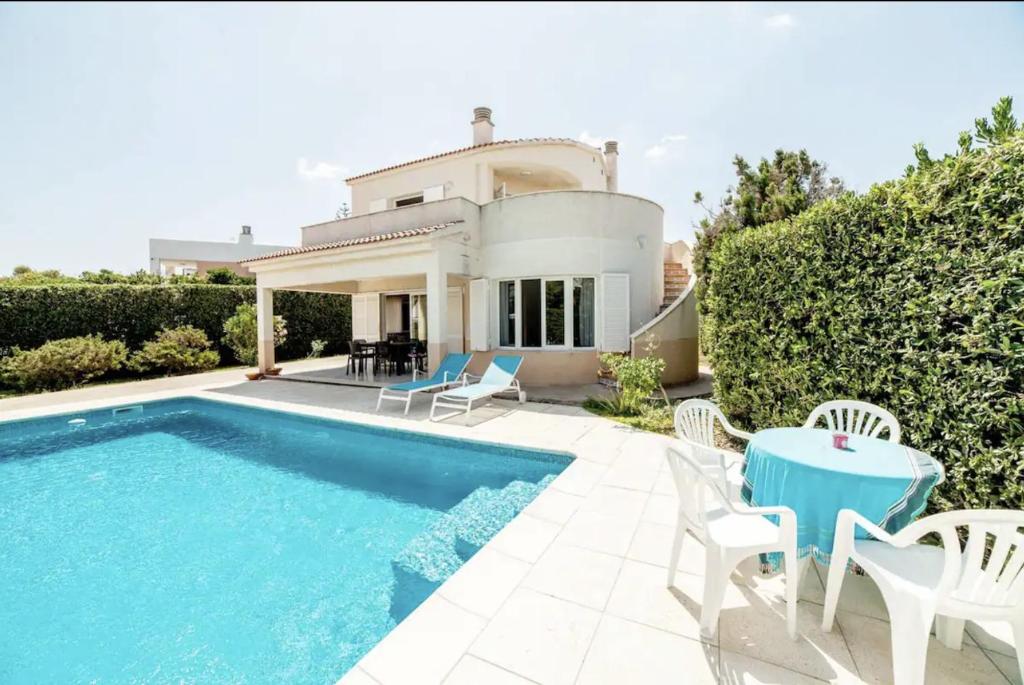 a villa with a swimming pool and a house at Villa with pool in Cala Blanca with sea views in Cala Santandria