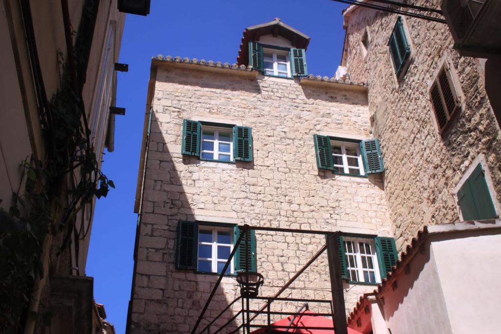 a tall stone building with green shuttered windows at Rooms Toni Palace in Split