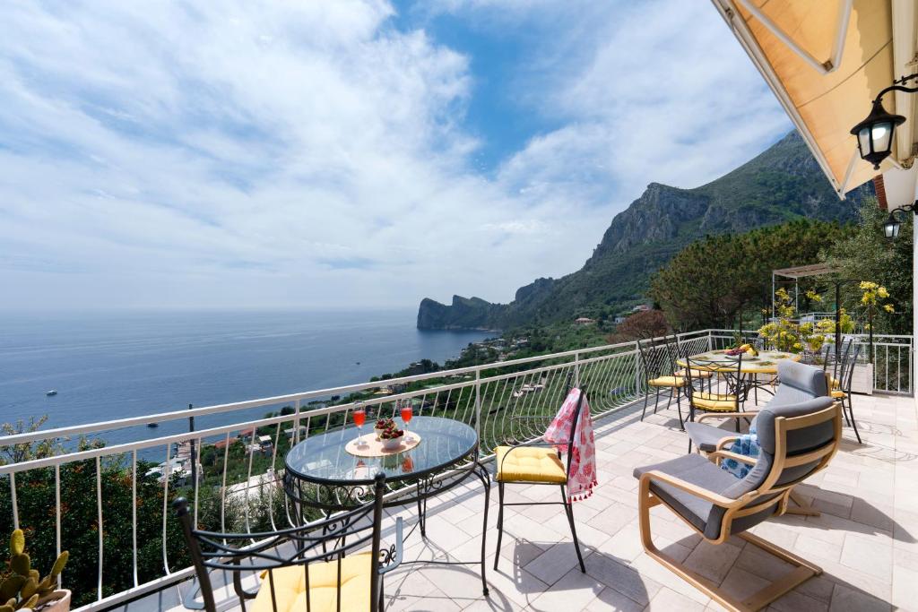 balcón con mesa, sillas y vistas al océano en Belvedere apartament stunning sea view, en Nerano